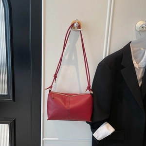 Minimalist red leather shoulder bag with fine knotted strap and gold metal accents
