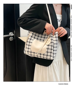 Detail of tweed houndstooth tote bag featuring a cute cat charm and contrast pocket