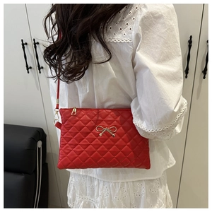 Détail macro du sac en cuir PU rouge matelassé avec fermoir nœud doré et fermeture