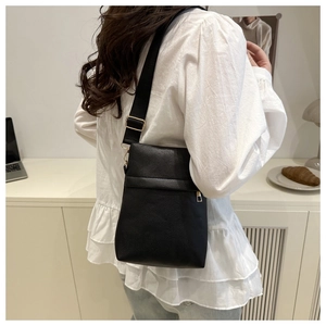 Close-up of black lychee grain leather crossbody bag with golden zipper and strap detail
