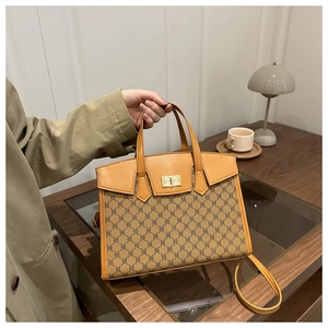 Detail of vintage tote bag with classic pattern, brown leather trim and gold twist lock