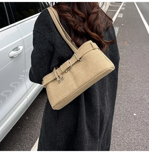 Detail of khaki textured shoulder bag with metallic buckle shown in a street style setting