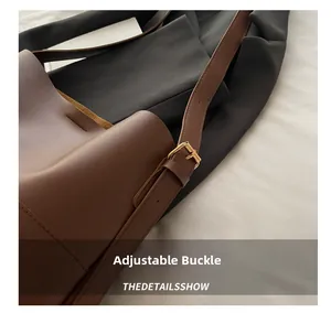 Detail view of the adjustable golden buckle on a brown leather bucket shoulder bag