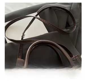 Close-up of adjustable strap with gold buckles on a brown patterned leather handbag