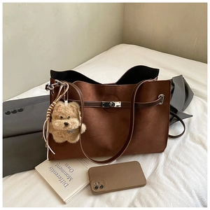 Detail of brown suede tote bag with metallic twist lock and cute plush puppy charm