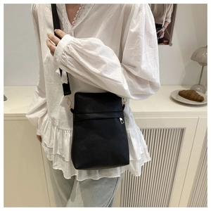 Detail of black pebbled leather crossbody phone bag with adjustable nylon wide strap