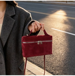 Detail of burgundy suede mini square bag featuring silver heart-shaped zipper pulls