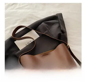 Detail of dark brown leather bucket bag showing matte texture and fine stitching work