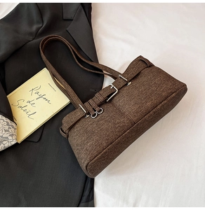 Detail of dark brown vintage shoulder bag with textured fabric and dual metal buckles
