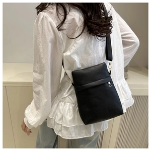 Close-up of black litchi texture crossbody bag with wide strap and gold hardware accents