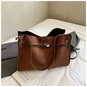 Detail of dark brown suede tote bag with silver twist-lock and decorative straps