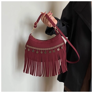 Detail view of burgundy suede handbag with fringe tassels and woven geometric straps