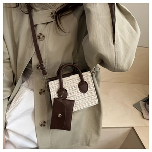 Detail of woven straw mini bag with brown leather handles and small coin purse charm
