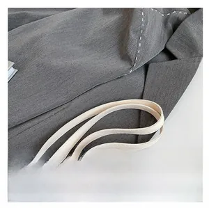 Close-up of grey textured tote bag with contrast white stitching and sleek shoulder strap