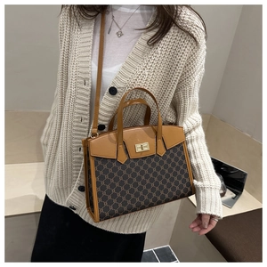 Detail of vintage monogram shoulder bag with gold clasp shown on a beige outfit