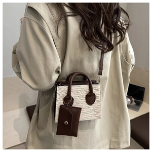 Detail view of woven straw shoulder bag with brown leather strap and mini pouch charm