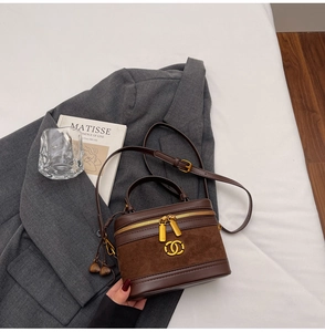 Detail of a brown leather crossbody bag with top handle and vintage gold zipper hardware