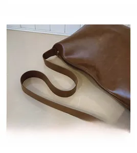 Detail of wide reinforced shoulder strap on dark brown vintage faux leather tote bag