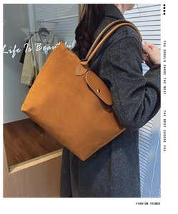 Close-up of brown suede tote bag with leather strap and metal magnetic clasp detail