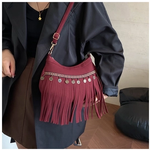Detail of burgundy suede moon bag featuring ethnic weaving and long tassel accents