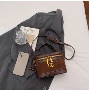 Close-up of brown leather crossbody bag with dual-texture finish and golden metal logo