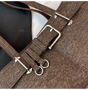 Close-up of brown textured canvas fabric with silver buckle and detailed stitching
