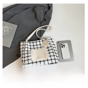 Detail of tweed tote bag featuring houndstooth pattern and leather pocket with cat charm