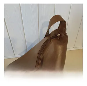 Close-up of smooth metal zipper detail on brown leather tote bag with elegant texture