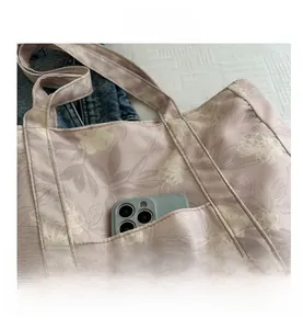 Detail of floral canvas tote bag featuring front pocket with smartphone for size reference