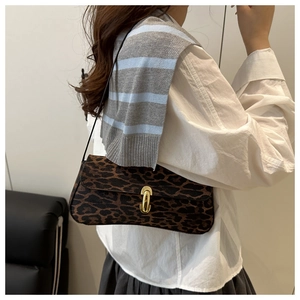 Close-up of leopard print underarm bag with gold oval clasp worn by a model