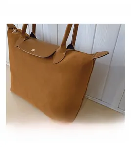Detail of caramel suede tote bag with brown leather flap and secure metallic button