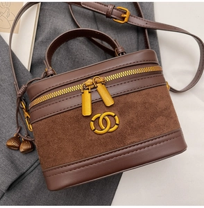 Detail of a brown leather and suede crossbody bag with gold hardware and logo