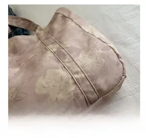 Detailed macro view of woven fabric texture and stitching on floral pink tote bag
