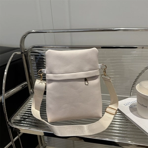 Minimalist white lychee leather crossbody bag with wide strap on modern silver shelf