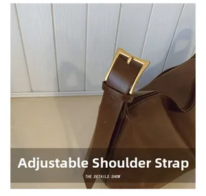Detail of adjustable shoulder strap with matte gold square buckle on retro brown bag