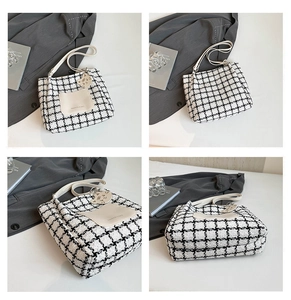 Detail view of black and white tweed tote bag with cat charm and front pocket detail