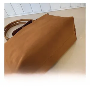 Detailed view of caramel brown leather tote bag with double stitching and snap button flap