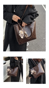 Detail of dark brown vintage texture tote bag with a cute plush cat charm for daily commute