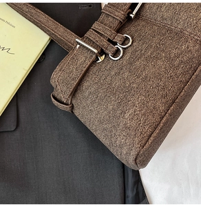 Detailed view of the brown textured fabric handbag with silver metal buckle accents