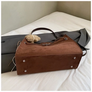 Brown suede tote bag with protective silver metal feet and plush pompom charm detail