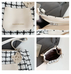 Detail view of tweed tote bag featuring gold logo, zipper closure and cute cat charm