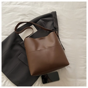 Detail of cross stitching on dark brown leather bucket bag with retro minimalist design