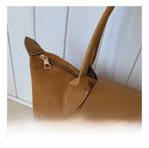 Detailed macro view of the smooth golden zipper and premium suede texture on the handbag