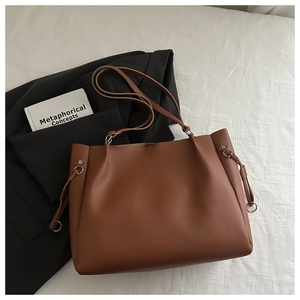 Detail of caramel tote bag showing matte leather texture and side metal ring accents