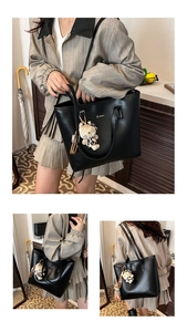 Detail view of large black textured leather tote bag with a leopard cat plush charm
