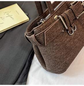 Close-up of brown woven texture handbag featuring a silver buckle and zipper detail