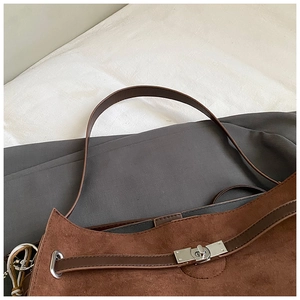 Detail of vintage brown suede tote bag with silver metal turn-lock and leather strap