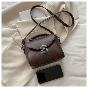 Detail of dark brown retro square bag with metal clasp and textured PU leather