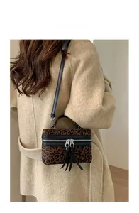 Mannequin portant un sac boîte léopard avec zips argentés et détails de franges