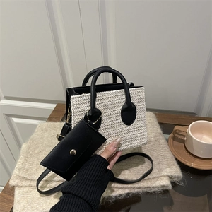 Straw tote bag with black leather straps and mini pouch on cozy wooden background